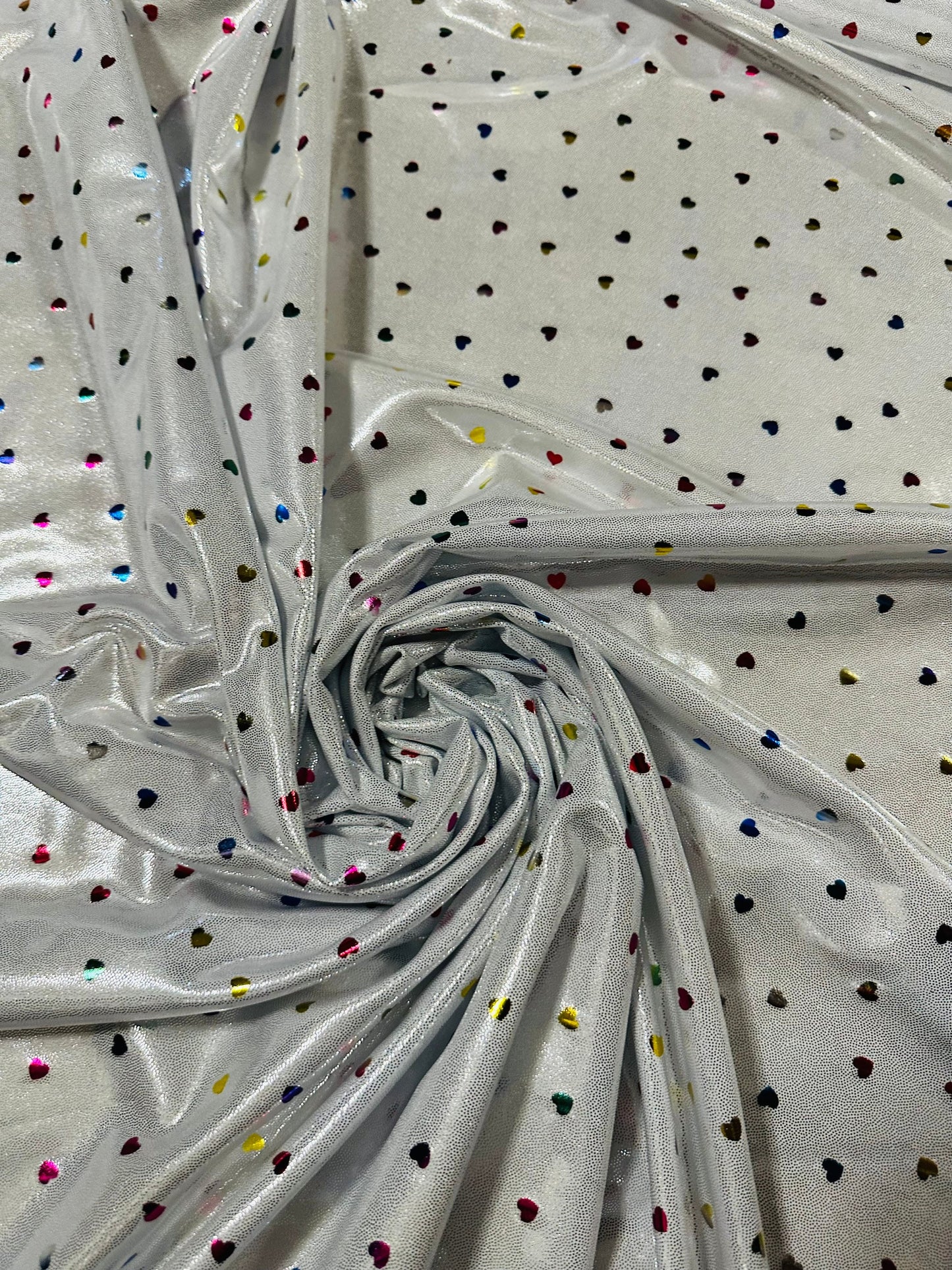Baby Hearts design rainbow color on silver foggy foil metallic hologram nylon spandex 4-way stretch 58/60” Sold by the YD.