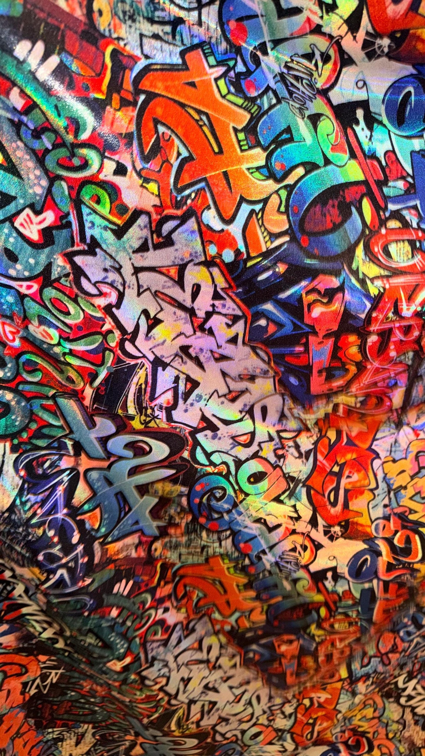 Graffiti design Multicolor on Iridescent metallic hologram nylon spandex  4-way stretch 58/60” Sold by the YD.  High quality fabrics