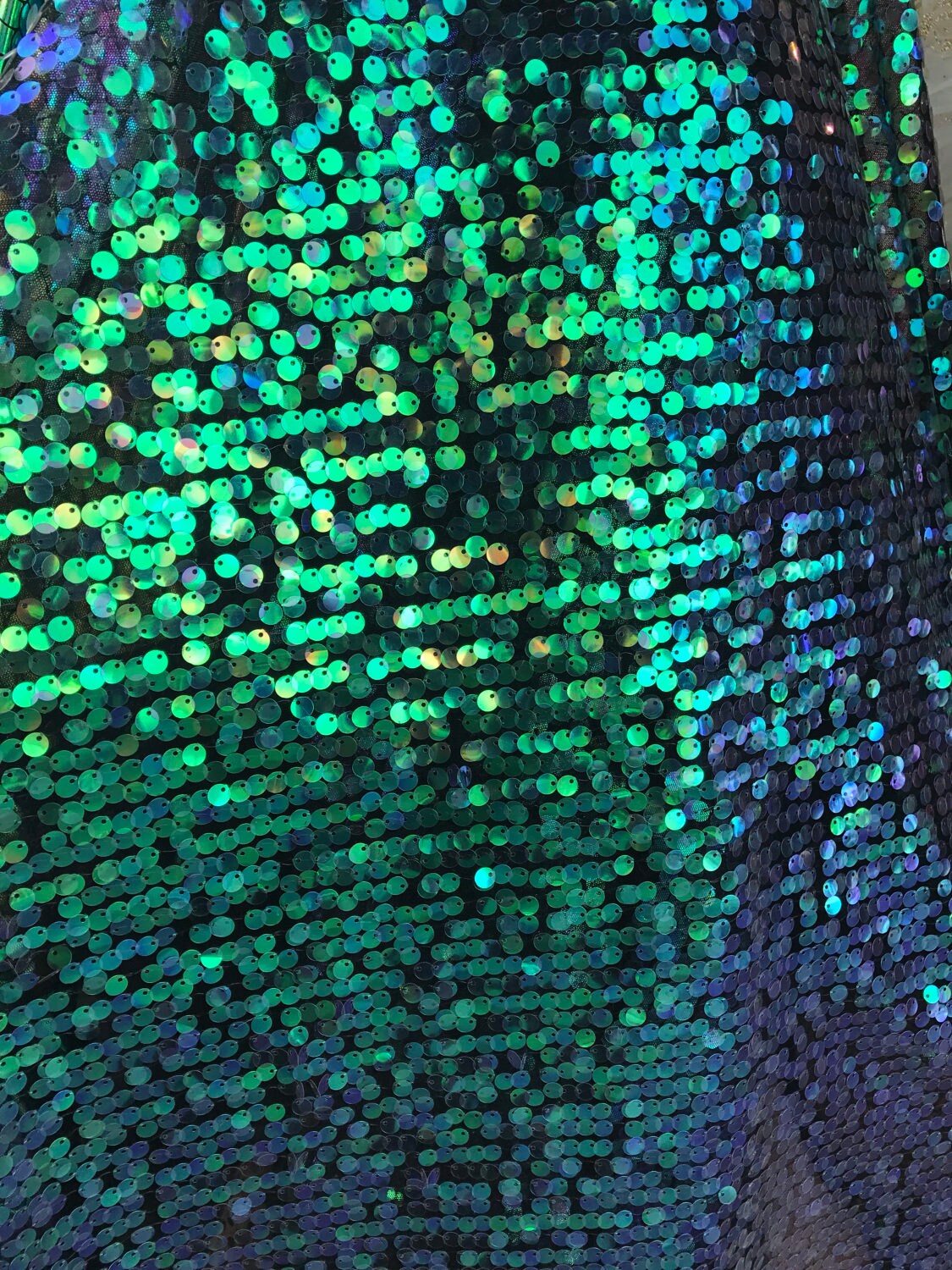 Iridescent green sequins medium size 10mm sequins on spandex mesh base 58/60" Sold by the YD. Ships worldwide from Los Angeles CA